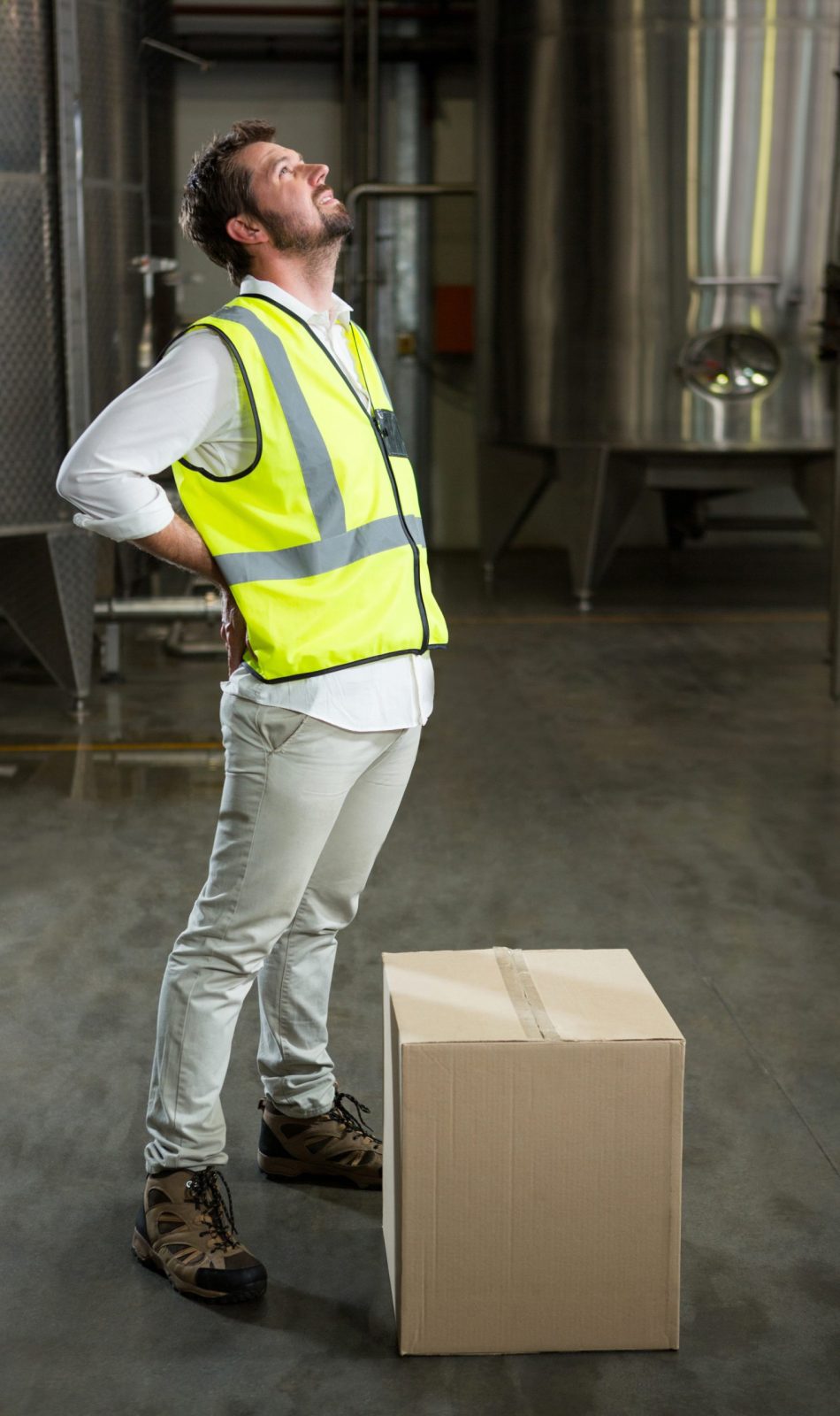 Full length of tired male worker standing in warehouse Full length of tired male worker standing in warehouse